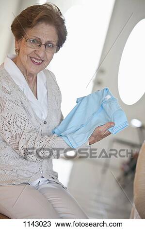 A senior woman holding a blue baby t-shirt View Large Photo Image Stock Image - A senior woman holding a blue baby t-shirt. Fotosearch