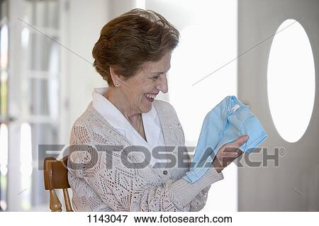 Stock Photo - A senior woman holding a blue baby t-shirt. Fotosearch