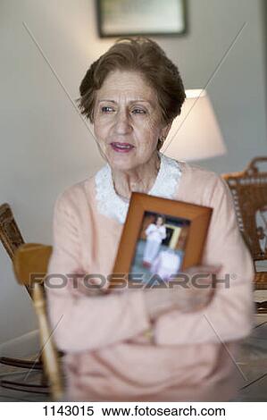 Stock Photography - A senior woman holding a picture frame. Fotosearch