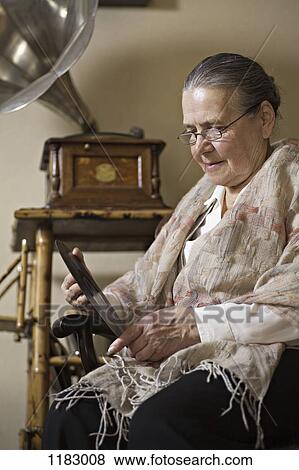 A senior woman looking intently at a vinyl record, gramophone in background View Large Photo Image Stock Photo - A senior woman looking intently at a vinyl record, gramophone in background. Fotosearch