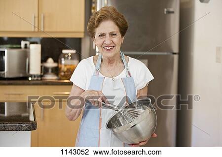 Stock Image - A senior woman mixing ingredients in a bowl. Fotosearch