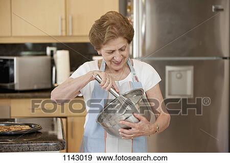A senior woman mixing ingredients in a bowl View Large Photo Image Stock Photo - A senior woman mixing ingredients in a bowl. Fotosearch