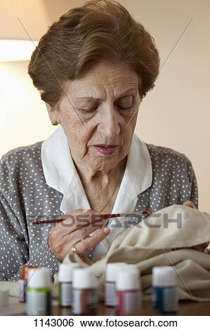 A senior woman painting on fabric View Large Photo Image Stock Photograph - A senior woman painting on fabric. Fotosearch
