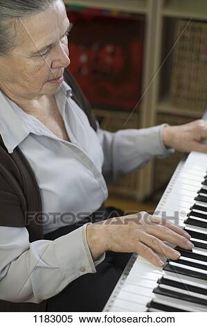A senior woman playing an upright piano View Large Photo Image Stock Photography - A senior woman playing an upright piano. Fotosearch