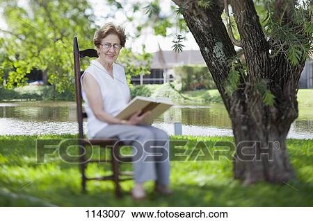 A senior woman reading next to a river View Large Photo Image Stock Photo - A senior woman reading next to a river. Fotosearch
