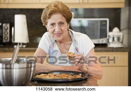 Stock Photo - A senior woman with freshly baked cookies. Fotosearch