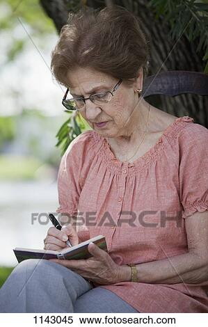 A senior woman writing in a book View Large Photo Image Stock Photography - A senior woman writing in a book. Fotosearch