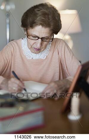 A senior woman writing in a note book View Large Photo Image Stock Photograph - A senior woman writing in a note book. Fotosearch