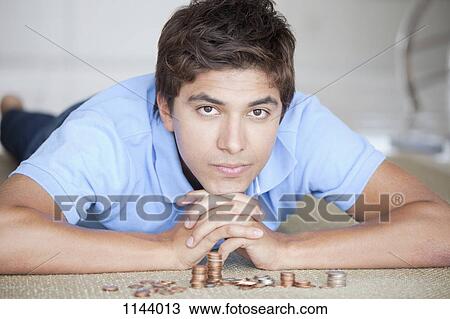 A serious man lying on the floor near stacks of coin View Large Photo Image Stock Image - A serious man lying on the floor near stacks of coin. Fotosearch