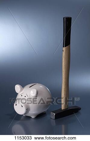 Stock Image - A sledgehammer next to a ceramic piggy bank. Fotosearch