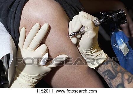 A tattoo artist preparing to tattoo a man's bare arm, close-up View Large Photo Image Stock Image - A tattoo artist preparing to tattoo a man's bare arm, close-up. Fotosearch