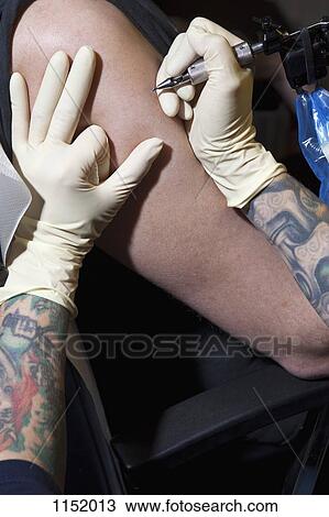 A tattoo artist preparing to tattoo a man's bare arm, close-up View Large Photo Image Stock Image - A tattoo artist preparing to tattoo a man's bare arm, close-up. Fotosearch