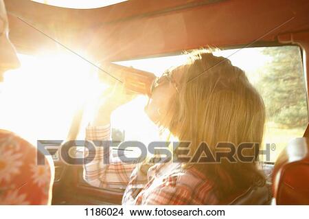 A woman drinking from a can while sitting in the passenger seat of vintage car View Large Photo Image Picture - A woman drinking from a can while sitting in the passenger seat of vintage car. Fotosearch