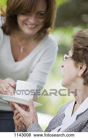 A woman handing a senior woman a cup of tea View Large Photo Image Stock Photo - A woman handing a senior woman a cup of tea. Fotosearch