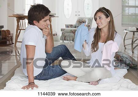 A woman holding up a pink and a blue baby shirt for her boyfriend to choose View Large Photo Image Stock Photo - A woman holding up a pink and a blue baby shirt for her boyfriend to choose. Fotosearch