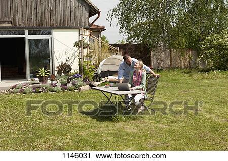 A woman laughing with her boyfriend while using a laptop in her backyard View Large Photo Image Stock Image - A woman laughing with her boyfriend while using a laptop in her backyard. Fotosearch