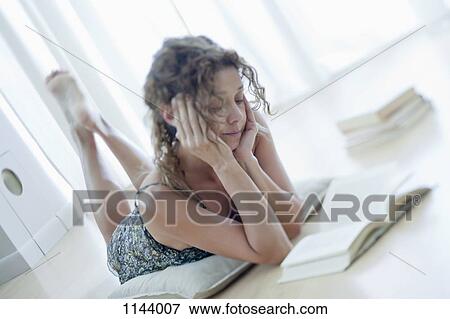 A woman lying on a floor reading a book View Large Photo Image Stock Photo - A woman lying on a floor reading a book. Fotosearch