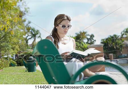 A woman reading a book on a park bench View Large Photo Image Stock Photo - A woman reading a book on a park bench. Fotosearch