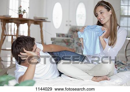 A woman showing a blue baby shirt to her boyfriend View Large Photo Image Stock Photo - A woman showing a blue baby shirt to her boyfriend. Fotosearch
