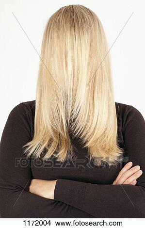 Picture - A woman standing with her long, blond hair combed forward covering her face. Fotosearch