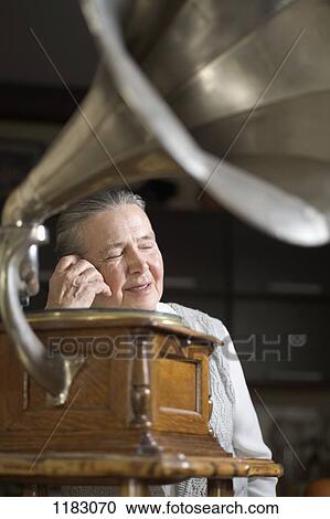 A woman with her eyes closed listening to a gramophone View Large Photo Image Stock Image - A woman with her eyes closed listening to a gramophone. Fotosearch