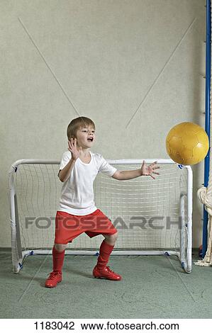 Stock Image - A young boy defending a goal while a ball flies towards him. Fotosearch