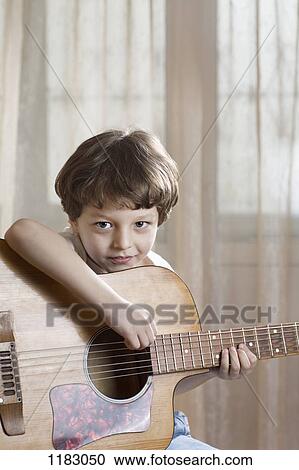 Stock Image - A young boy holding an acoustic guitar. Fotosearch