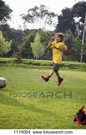 A young boy jumping in mid-air on a soccer field View Large Photo Image Picture - A young boy jumping in mid-air on a soccer field. Fotosearch