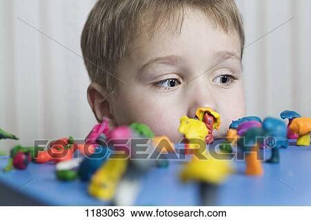 A young boy looking at various shapes made from child's play clay View Large Photo Image Stock Image - A young boy looking at various shapes made from child's play clay. Fotosearch