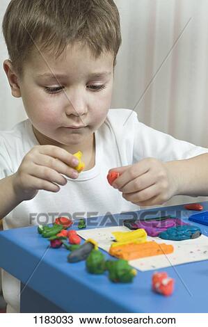 A young boy playing with various colored child's play clay View Large Photo Image Stock Image - A young boy playing with various colored child's play clay. Fotosearch