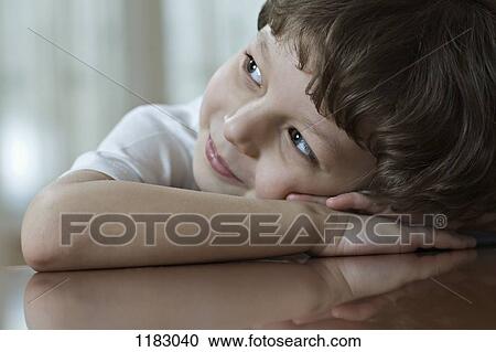 A young boy resting his head on his clasped hands, looking up and away View Large Photo Image Stock Image - A young boy resting his head on his clasped hands, looking up and away. Fotosearch