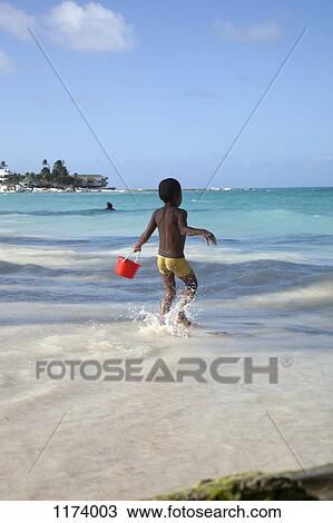 A young boy running towards the sea holding a sand pail View Large Photo Image Stock Image - A young boy running towards the sea holding a sand pail. Fotosearch