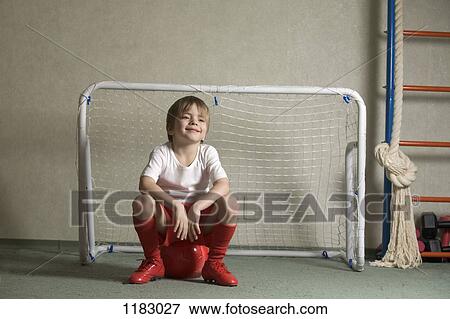 A young boy sitting on a soccer ball in front of a soccer goal View Large Photo Image Stock Photo - A young boy sitting on a soccer ball in front of a soccer goal. Fotosearch