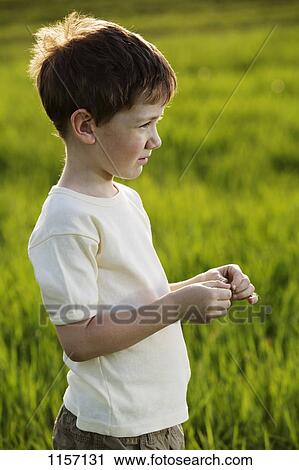 Stock Image - A young boy standing in a field. Fotosearch