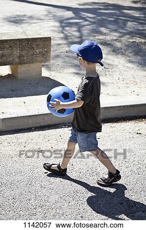A young boy walking with a ball View Large Photo Image Stock Photo - A young boy walking with a ball. Fotosearch