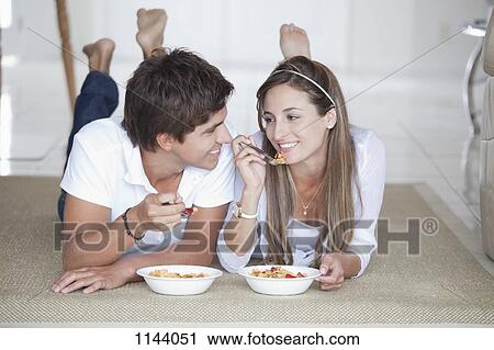 Stock Image - A young couple flirting over their bowels of cereal. Fotosearch