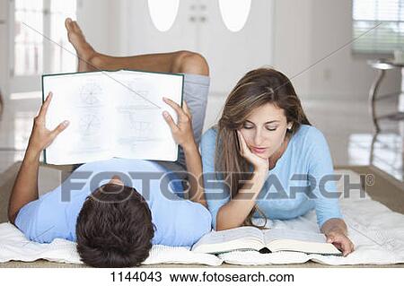 A young couple lying on the floor reading textbooks View Large Photo Image Stock Image - A young couple lying on the floor reading textbooks. Fotosearch