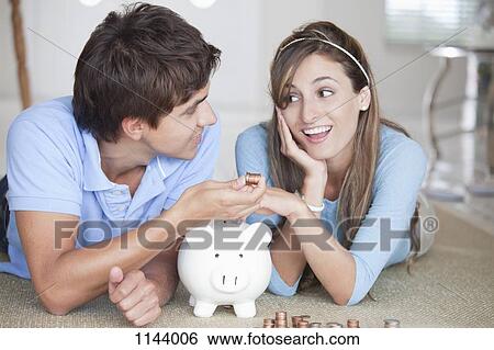 A young couple lying on the floor counting coins View Large Photo Image Stock Photograph - A young couple lying on the floor counting coins. Fotosearch