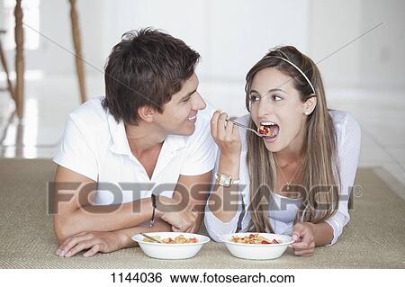 A young couple lying on the floor eating cereal for breakfast View Large Photo Image Stock Photograph - A young couple lying on the floor eating cereal for breakfast. Fotosearch