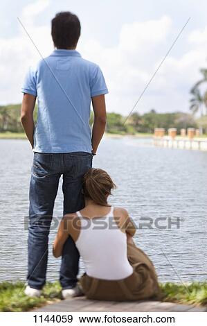 A young couple relaxing by a lake View Large Photo Image Stock Photo - A young couple relaxing by a lake. Fotosearch