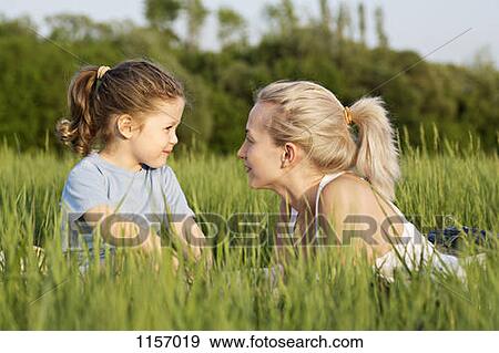 A young girl and a woman relaxing in a field together View Large Photo Image Stock Photo - A young girl and a woman relaxing in a field together. Fotosearch