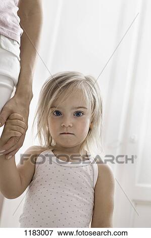 Stock Photo - A young girl holding her mother's hand, staring into the camera. Fotosearch