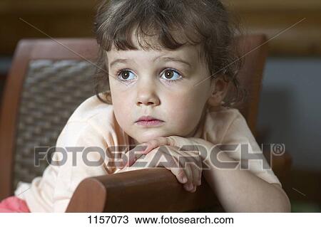 A young girl sitting on a chair and looking away View Large Photo Image Stock Image - A young girl sitting on a chair and looking away. Fotosearch