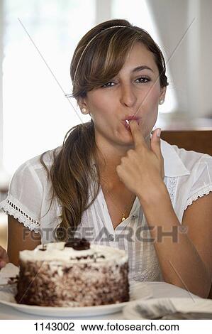 Stock Image - A young woman tasting a cake. Fotosearch