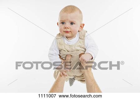 Stock Photo - An adult holding up a baby boy. Fotosearch