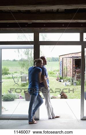 Stock Photo - An affectionate couple leaning in the doorway of their house. Fotosearch