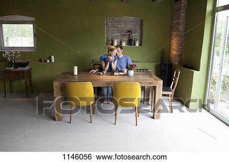 Stock Photograph - An affectionate couple sitting at a table with a personal organizer and coffee. Fotosearch