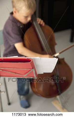 Boy playing cello with sheet music in the foreground View Large Photo Image Stock Image - Boy playing cello with sheet music in the foreground. Fotosearch