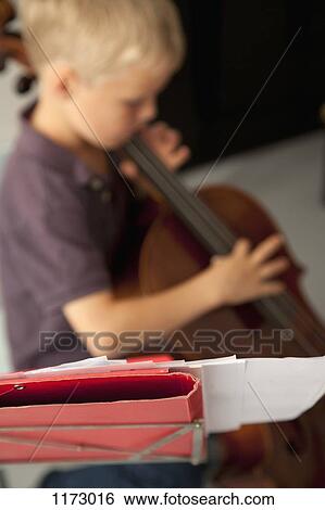 Boy playing cello with sheet music in the foreground View Large Photo Image Stock Photograph - Boy playing cello with sheet music in the foreground. Fotosearch