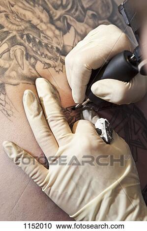 Close-up of a tattoo artist tattooing a design on human skin View Large Photo Image Stock Image - Close-up of a tattoo artist tattooing a design on human skin. Fotosearch